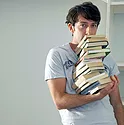 A student holding a tower of books